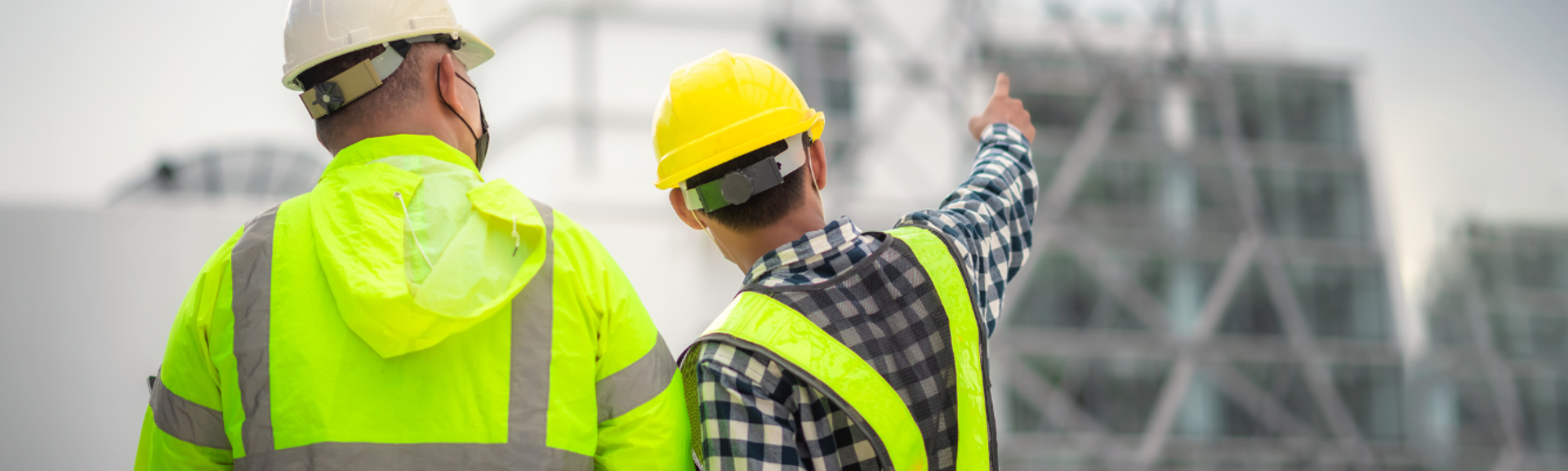Two construction workers pointing at a structure in the distance