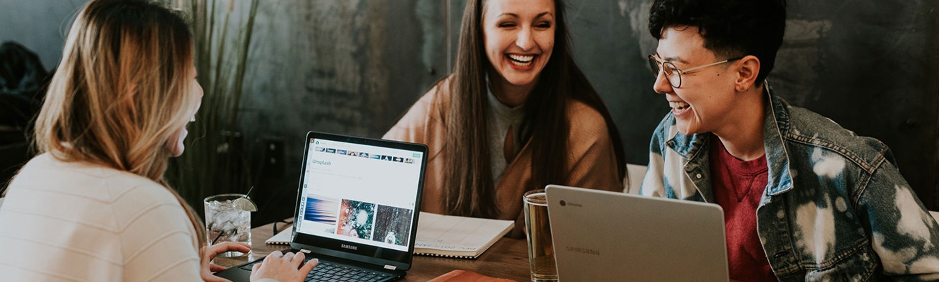 Three women working happily at a table together with laptops